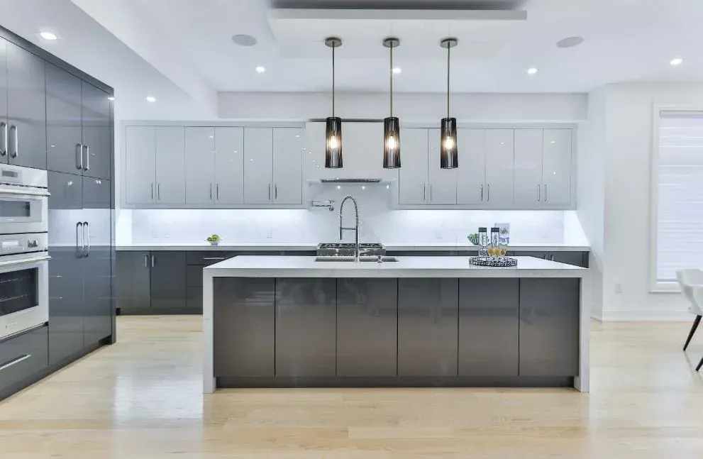 Grey and white kitchen with a white island beneath three black pendant lights