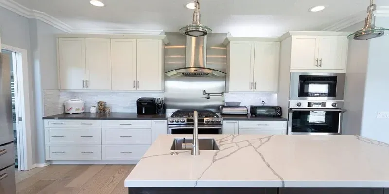 Wood cabinet kitchen with a granite-top island, stainless double ovens and patterned runner rugs on tile flooring