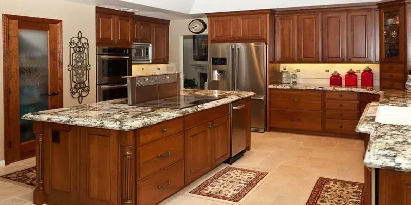 Cherry wood kitchen with a granite-topped island cooktop, double wall ovens and a stainless refrigerator
