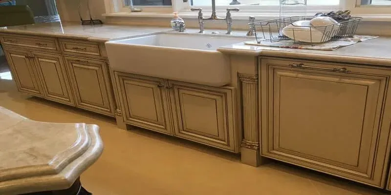 marble-look countertop with a white farmhouse sink, chrome faucet and a dish drying rack