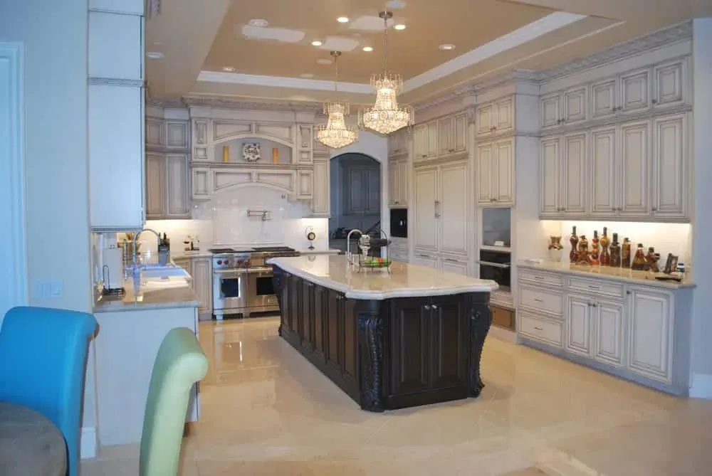Lake Forest kitchen with two crystal chandeliers over a dark carved island and glazed cabinetry