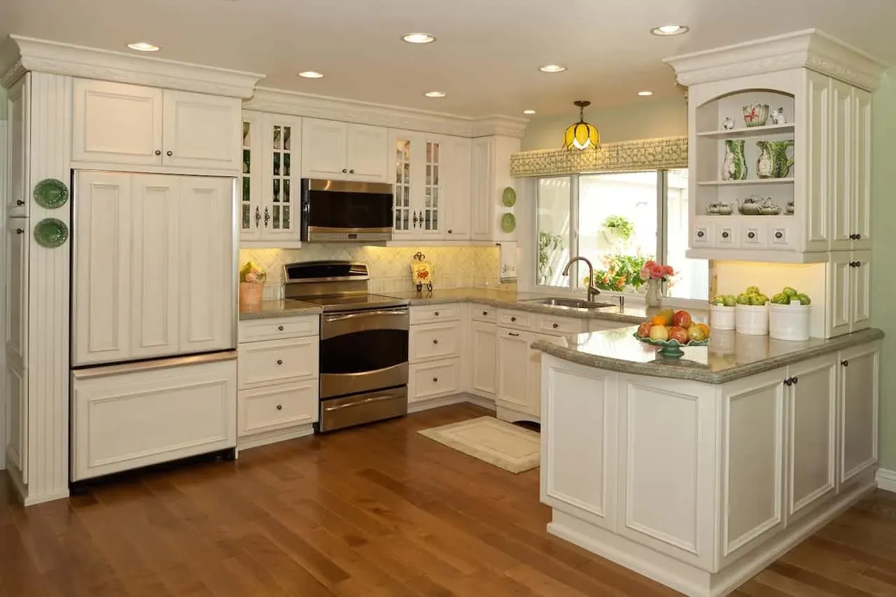 Cream painted cabinetry with glass-front uppers around a kitchen island on a wood floor in Fullerton