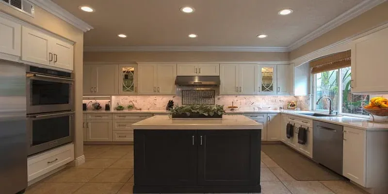 White kitchen with a dark centre island and stainless double wall ovens