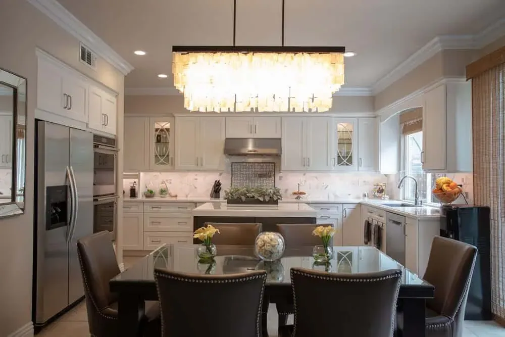 Cream kitchen with a linear crystal chandelier above a dining table