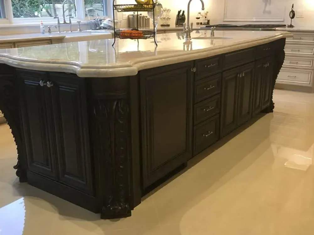 Lake Forest kitchen island in dark carved wood with a thick cream stone top and an ogee edge