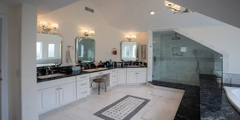 bathroom with a black-countertop double vanity, three framed mirrors and a glass-enclosed walk-in shower