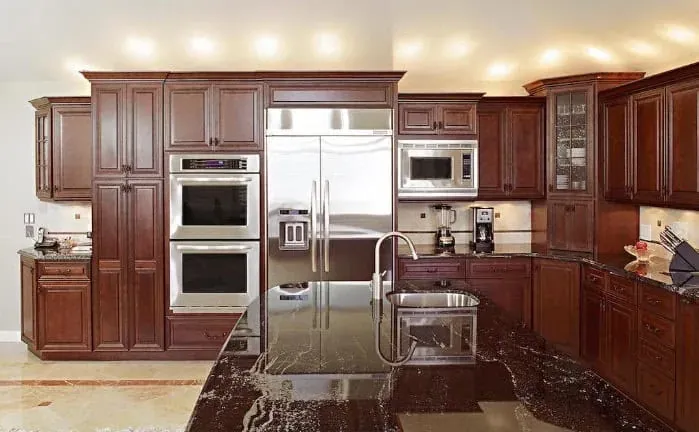 Cherry cabinet kitchen with stainless double wall ovens, a built-in refrigerator and a black granite island