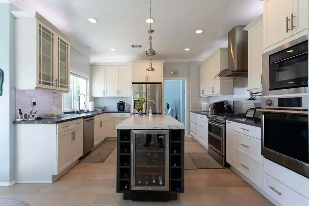 White kitchen with a wine-cooler island and a stainless chimney hood