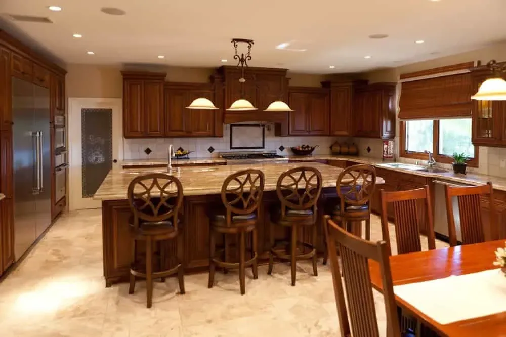 Cherry kitchen with a granite island, round-back stools and a dining table beside it