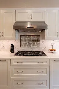white shaker cabinets with stainless range hood over gas cooktop and mosaic tile backsplash inset