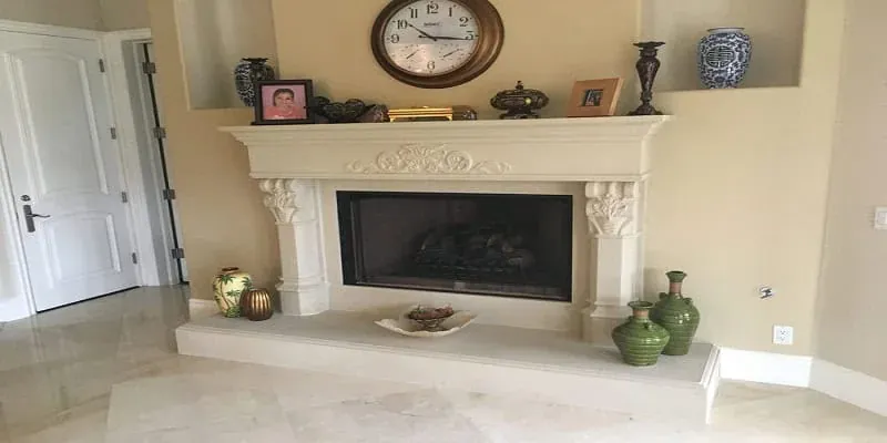 carved stone fireplace mantel with a wall clock, framed photographs and decorative ceramic vases