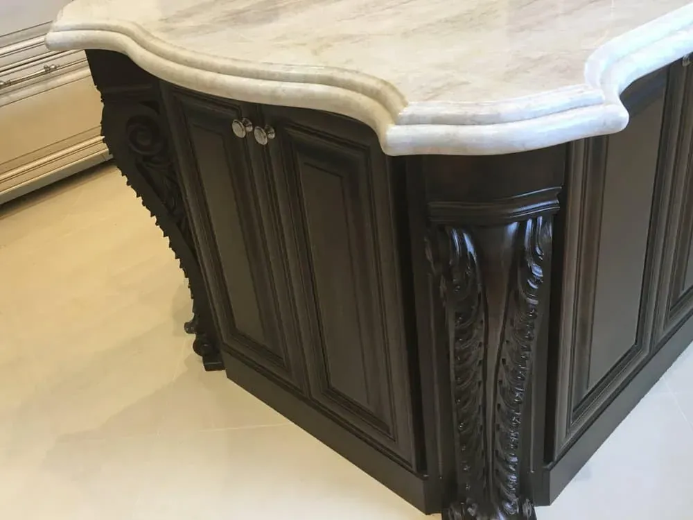 Dark carved island corner beneath a thick stone top