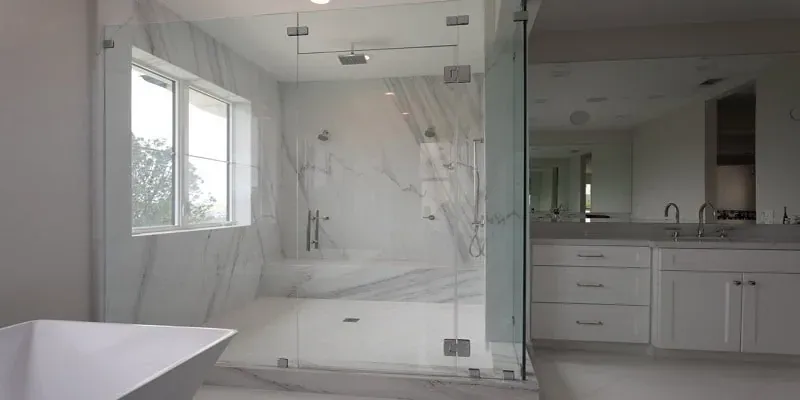 glass-enclosed walk-in shower with marble-look tile beside a white double vanity and a freestanding tub