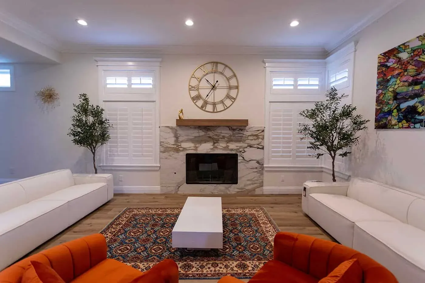 Yorba Linda living room with a stone fireplace wall, a wall clock and two olive trees