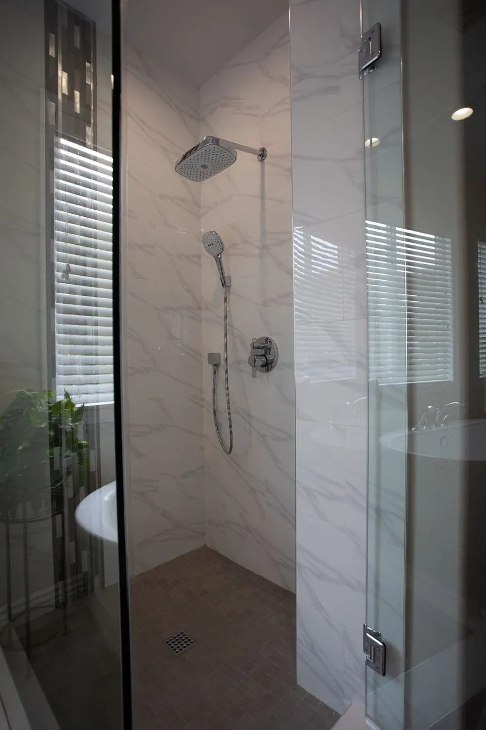 Irvine bathroom with a marble-tiled shower and a handheld shower behind a glass screen