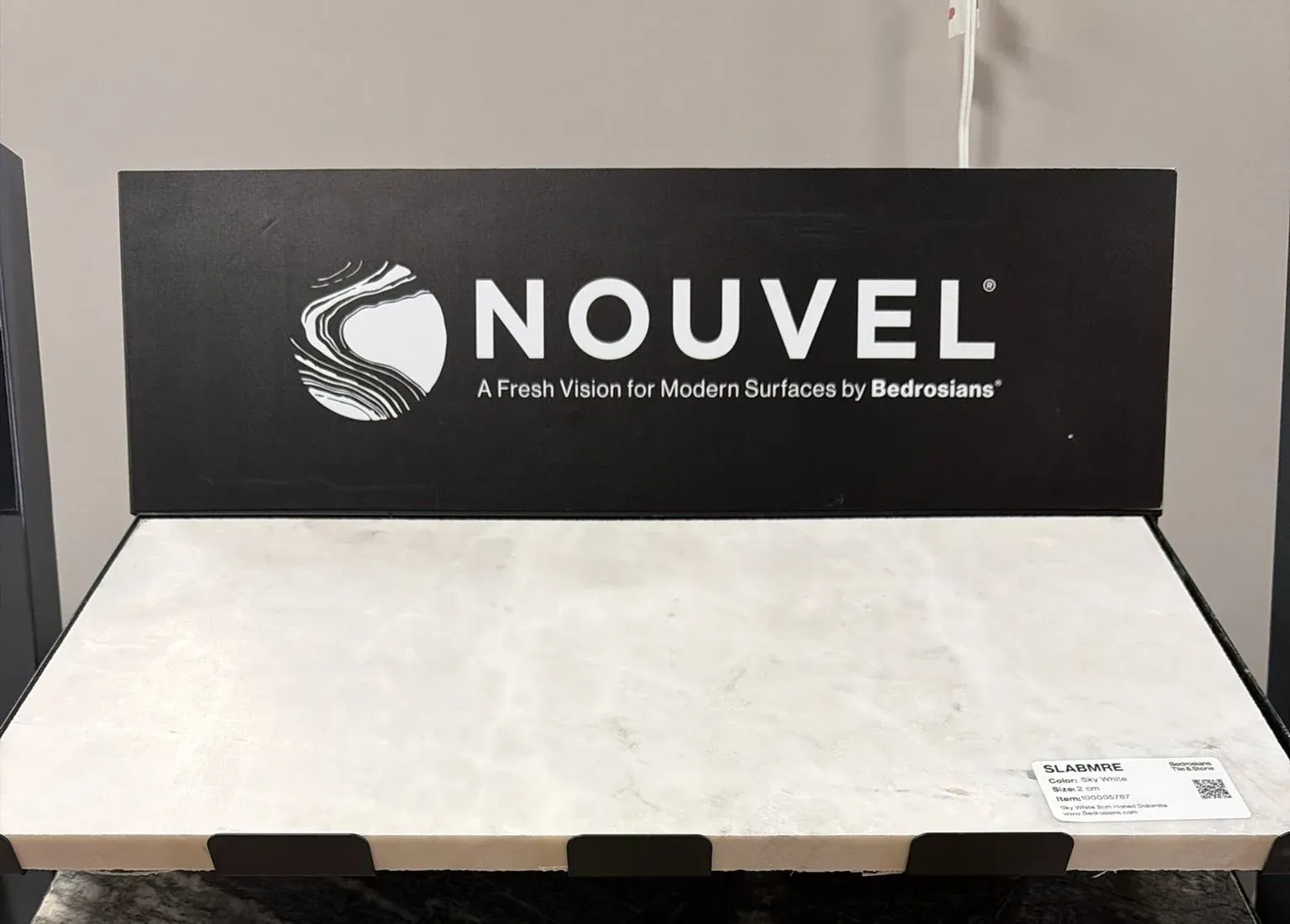Nouvel by Bedrosians display in the Anaheim showroom with pull-out stone slab samples stacked below the sign