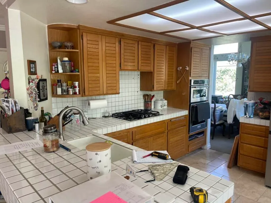 Oak cabinets and tile countertops before remodeling, with a gas cooktop and wall oven