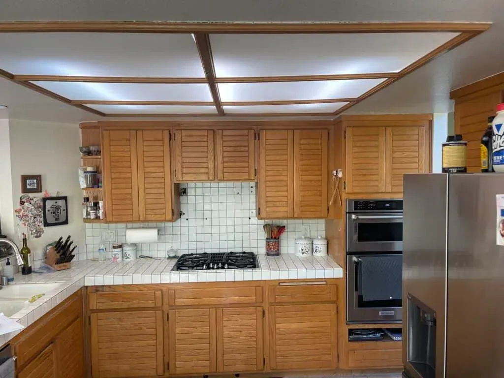 Anaheim kitchen before remodeling, with oak cabinets, tile counters, a gas cooktop and a lit ceiling grid above