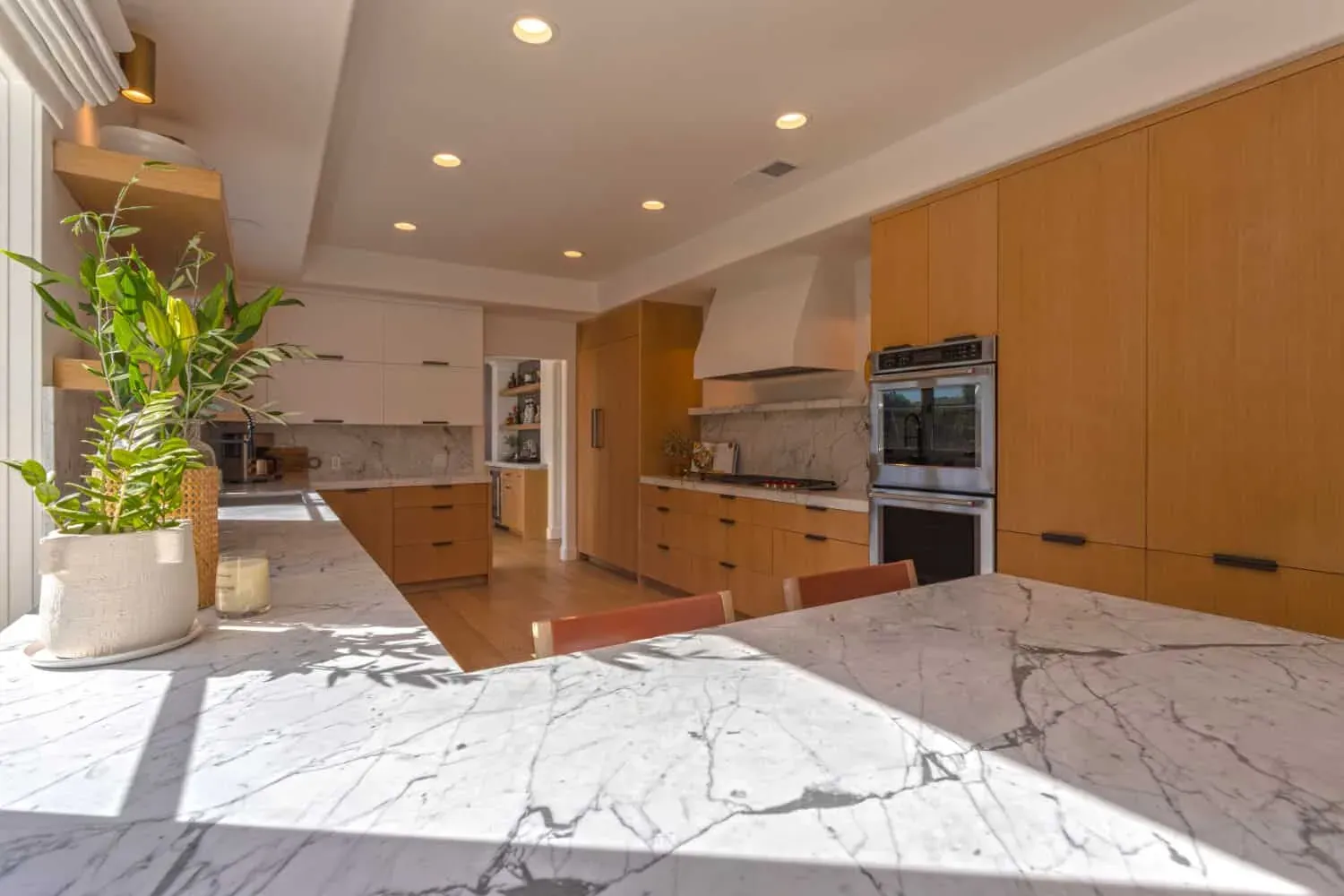 Oak kitchen with a plaster hood, open shelves and a veined marble island