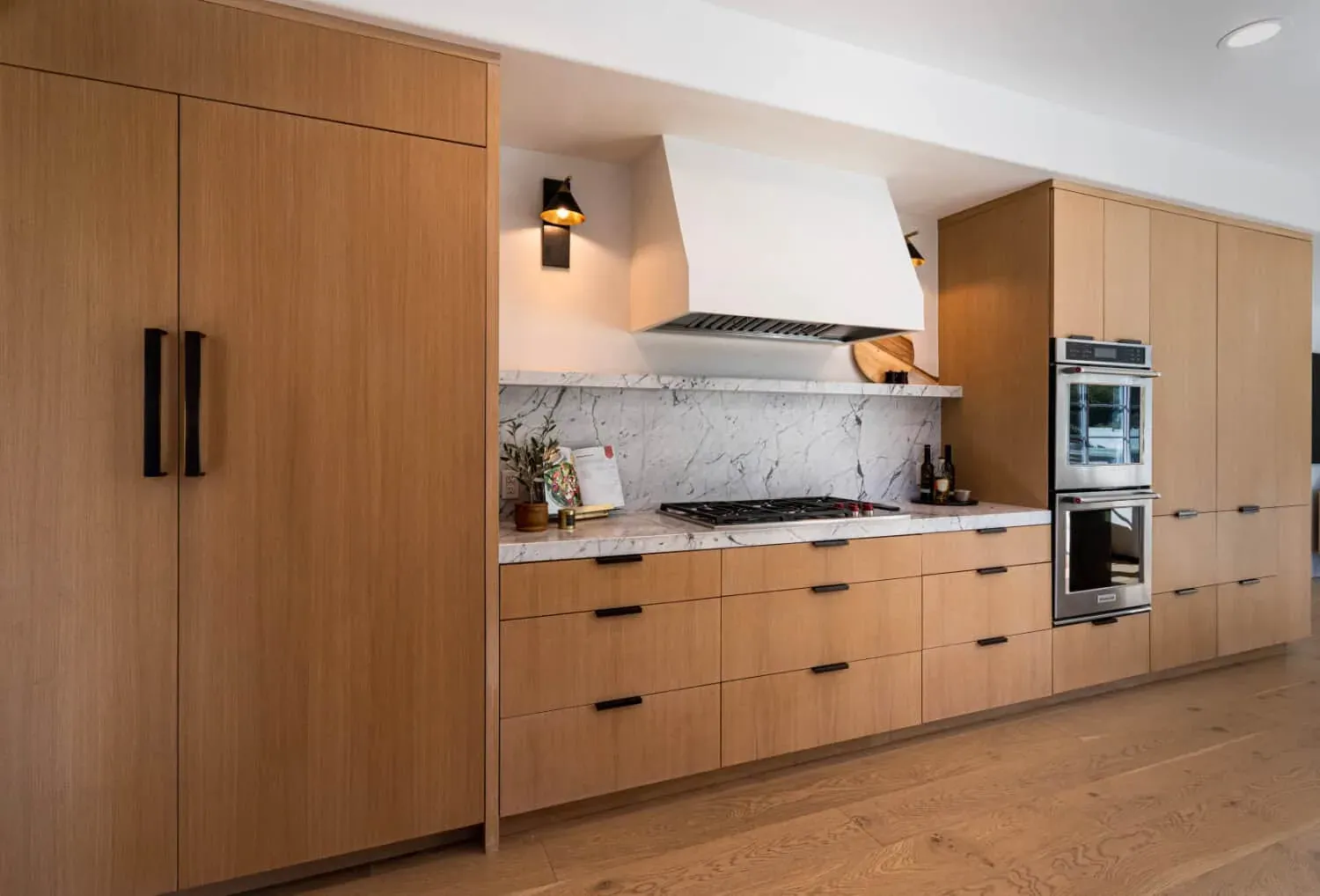 Anaheim oak kitchen with tall panelled cabinetry, a white plaster hood over the cooktop and double wall ovens