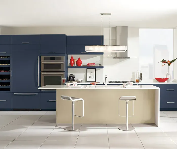 Omega Cabinetry photograph of a kitchen with navy painted full-height cabinets, stacked ovens and a light island, not a Kitchen Cabinets and Beyond project