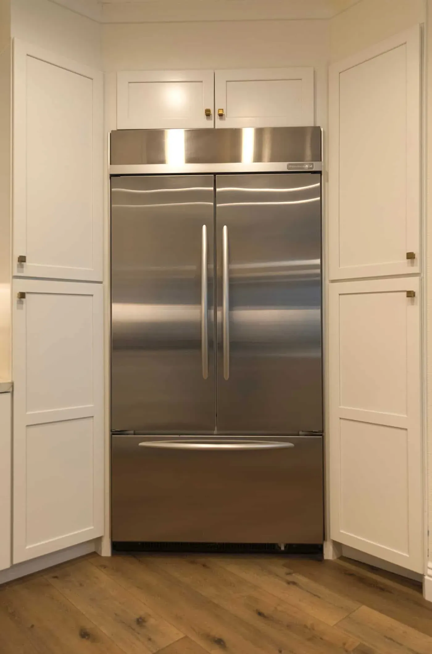 Tall white panelled cabinetry built to flank a stainless French-door refrigerator
