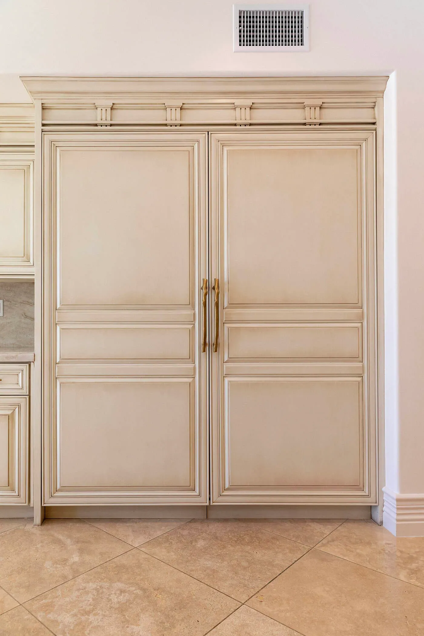 Tall panelled cream cabinet doors with long brass bar pulls and a glazed finish