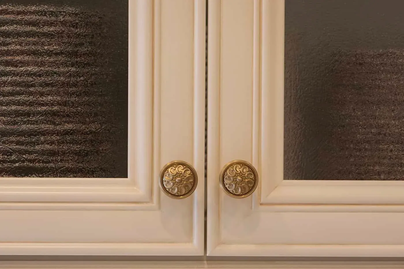 Cream cabinet doors with reeded glass panels and round carved brass knobs