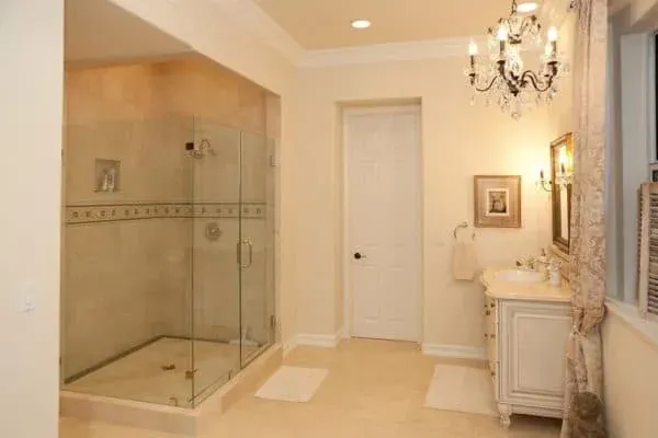 Tiled walk-in shower with a glass enclosure beneath a crystal chandelier