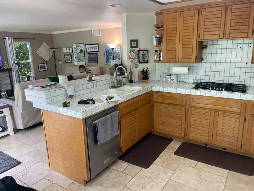 Anaheim kitchen before its remodel, with louvered oak cabinets and white tile countertops on a U-shaped run