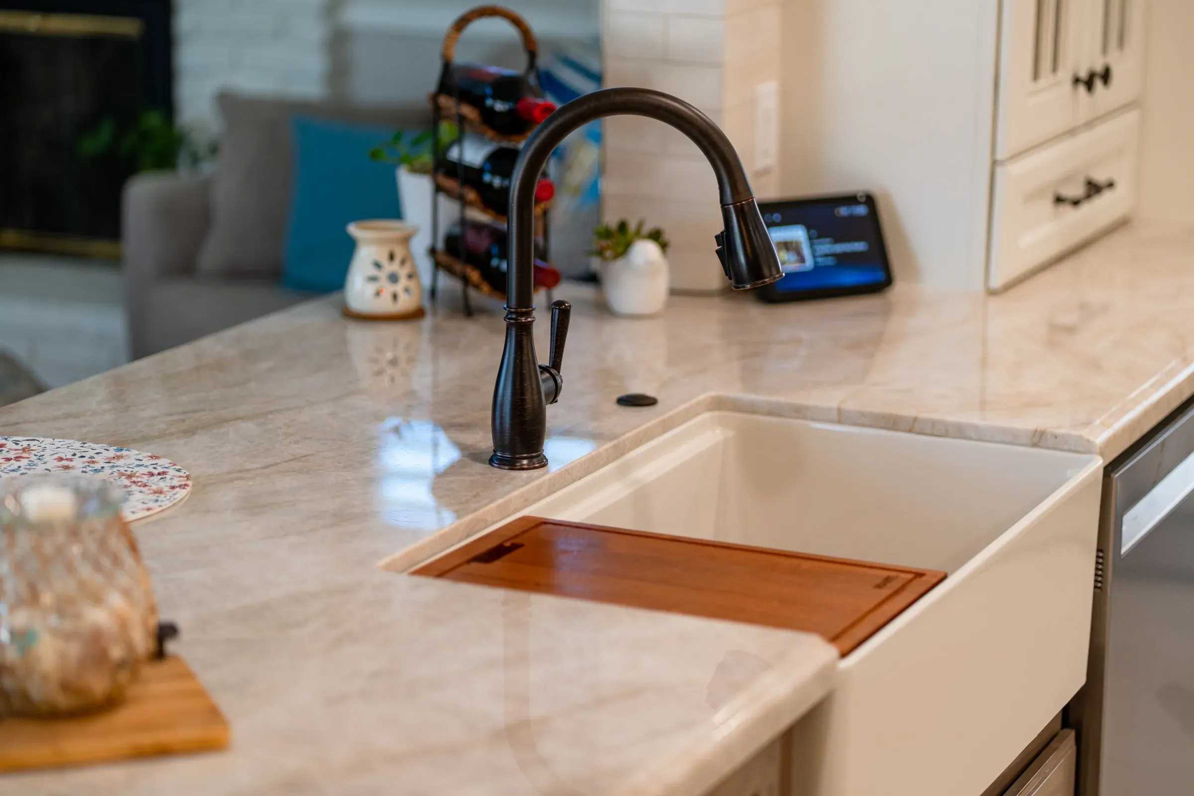 White farmhouse sink with a wood cutting board insert in a cream stone countertop