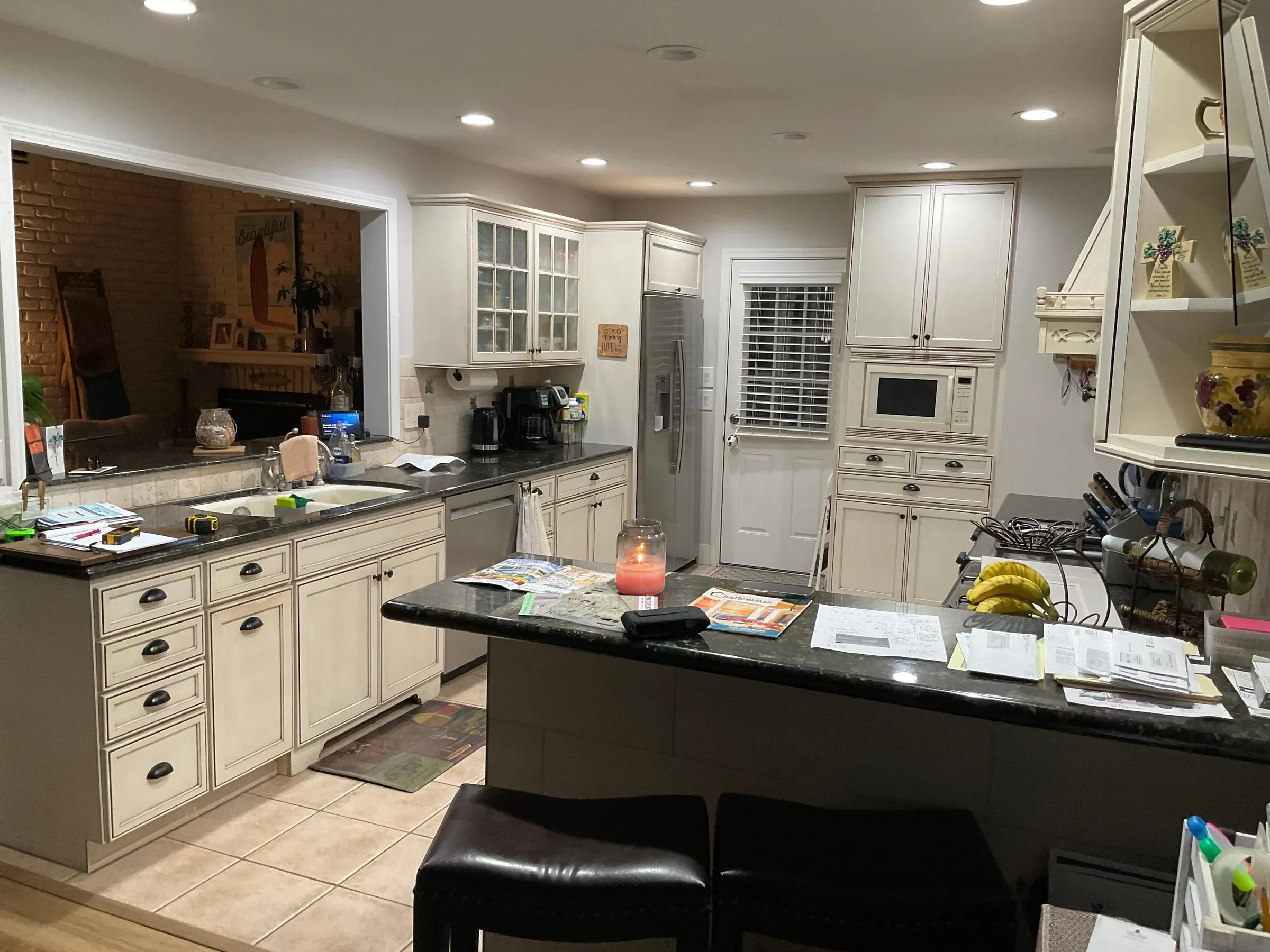 Westminster kitchen before the remodel, with glazed white cabinets and a dark granite peninsula with bar stools