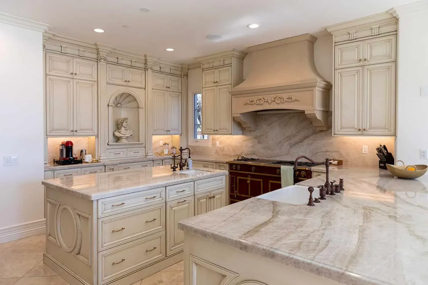 Cream traditional kitchen remodel with a carved range hood and a large stone island